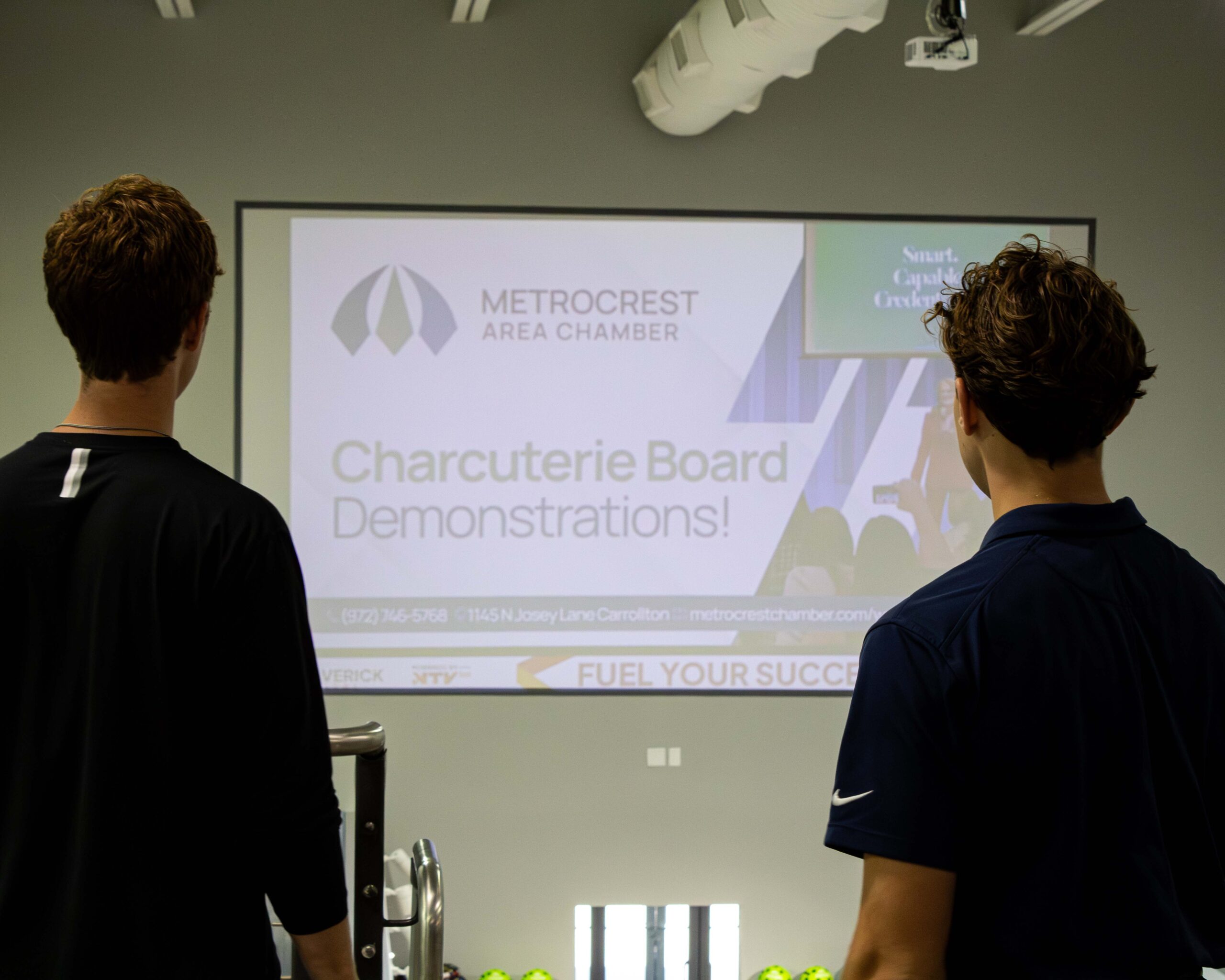 Maverick Digital team members viewing an indoor digital advertising display at a Metrocrest Area Chamber event.